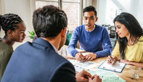 Starting a business Group of diverse colleagues gathered around a table reviewing documents, symbolizing a business team meeting.