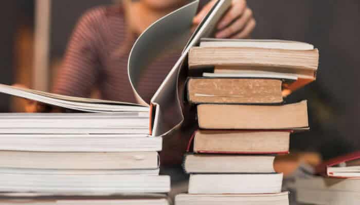 Used textbooks for social change | tycoonstory media Stack of books and student studying, highlighting education-focused programs supported by a social enterprise.