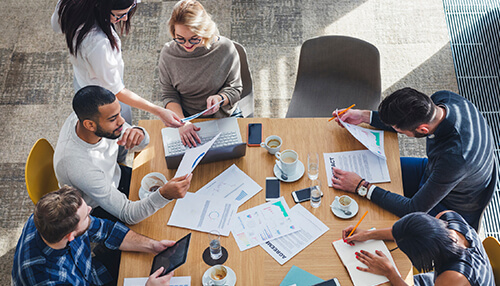 First time entrepreneurs First time entrepreneurs reviewing documents and planning business goals during a team brainstorming session.