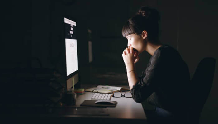 Dark side of being an entrepreneur A tired woman working late at a computer in a dim office, representing the late-night challenges of being an entrepreneur.