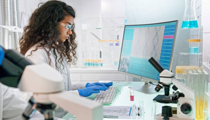 Canadian students Canadian students in a science lab analyzing dna data on a computer surrounded by microscopes and research equipment.
