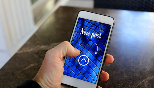 Post on social media : the best and worst times Person holding a smartphone with a new post notification, representing how to post on social media using mobile platforms for instant updates and sharing.