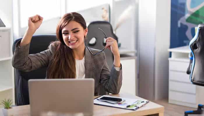 Be active - tycoonstory | tycoonstory media Happy office worker celebrating high traffic results on her laptop after an seo optimization campaign