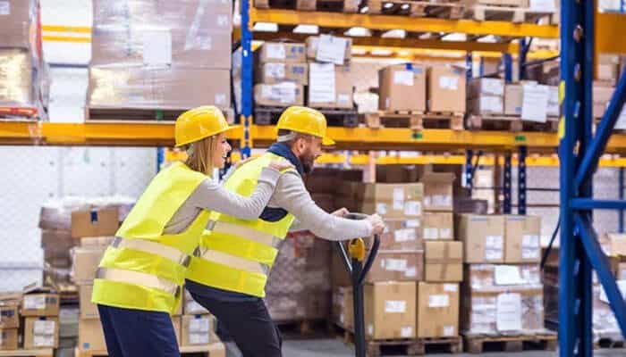 Have a safety manager - tycoonstory 1 | tycoonstory media Workers wearing safety helmets and vests handling warehouse equipment inside a manufacturing department.