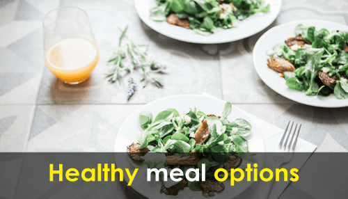 Employee-friendly office Healthy meal plates with mixed greens and juice served on a clean table promoting healthy meal options.