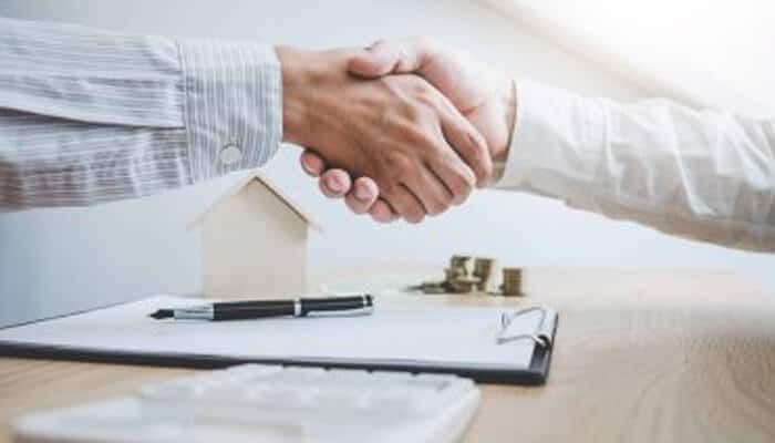 Figure out how quickly you need access to loan funds - tycoonstorymedia | tycoonstory media Two business professionals shaking hands over a loan agreement, symbolizing the partnership to secure the right loan for your startup.