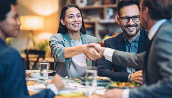 Stoic principles Business professionals smiling and shaking hands during a meeting, representing stoic principles in entrepreneurship and strong professional relationships.
