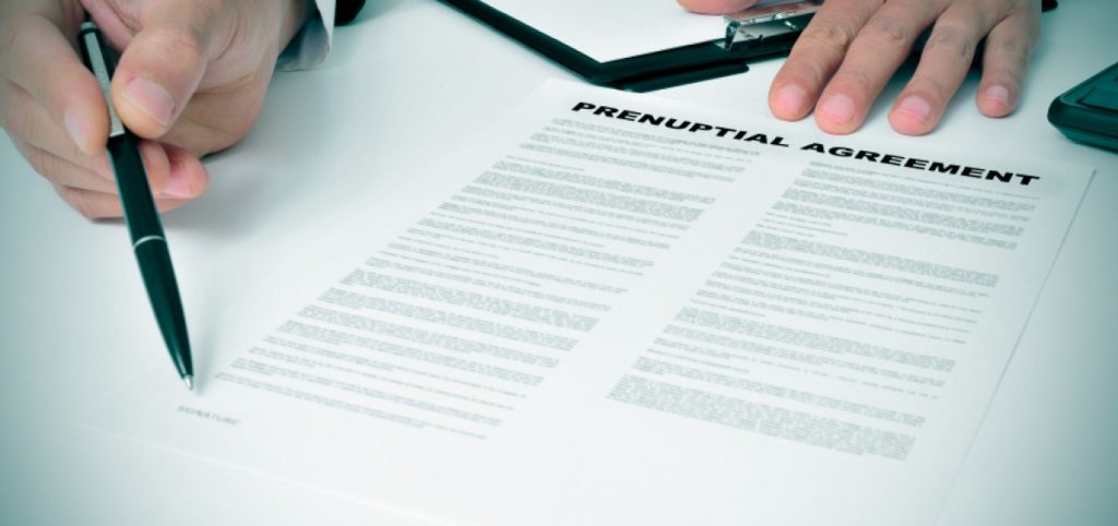 Share of entitlement - tycoonstory | tycoonstory media A close-up of a person holding a pen and preparing to sign a document labeled “prenuptial agreement,” representing legal planning and protections related to family law.