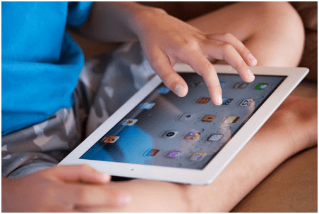 Educational app source -tycoonstory | tycoonstory media Close-up of a child’s hands navigating a tablet screen, demonstrating how educational apps support digital learning and engagement.