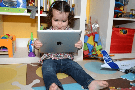 Educational apps Toddler sitting on the floor holding a tablet, exploring interactive educational apps designed for young learners.