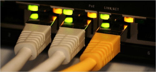 It network - tycoonstory | tycoonstory media Close-up of ethernet cables connected to a router with glowing indicator lights, representing a stable network connection.