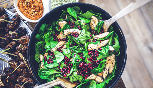 Food A fresh spinach salad with chicken and pomegranate seeds, a nutrient-packed meal that supports boosting energy for the day ahead.