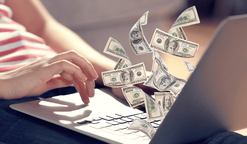 Writing for magazines Person typing on a laptop with illustrated dollar bills appearing to fly out, symbolizing earning money online.
