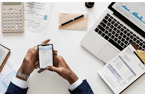 Private home loans -tycoonstory | tycoonstory media Businessman reviewing financial documents and mortgage details using a smartphone and laptop.