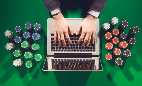 Alternative start-up ideas Person typing on a laptop surrounded by stacks of colorful poker chips on a green table.