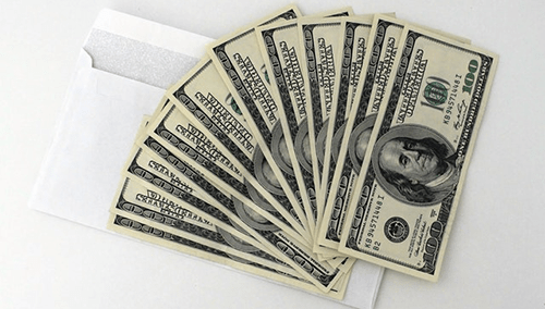 Currency Stack of u. S. Dollar bills fanned out beside an envelope, representing changing currency at a trusted exchange.