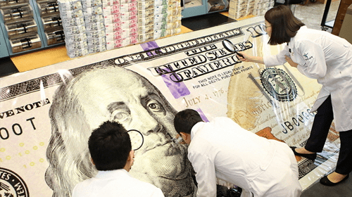 Experts People examining an oversized printed u. S. Hundred-dollar bill in a lab-like setting, highlighting currency verification processes supported by valuable customer feedback.