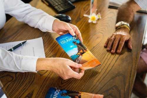 Tour guide A travel agent handing a vacation brochure across a wooden desk, showing career opportunities in travel planning.