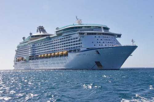 Make money A large white cruise ship sailing across the ocean, showcasing travel opportunities and jobs on cruise lines.