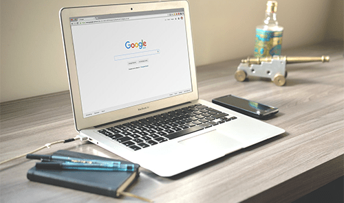 Seo google search results - tycoostory | tycoonstory media Laptop displaying google search results on a desk, representing organic search marketing in the seo vs ppc debate.