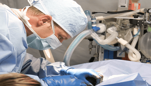 Patient - tycoonstory | tycoonstory media Surgeon in protective gear performing a medical procedure using advanced equipment.