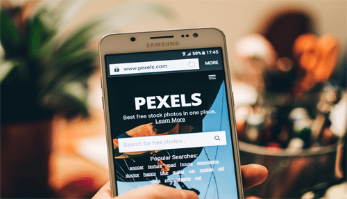 Pexels Image of a smartphone displaying the pexels website, showcasing a search for free stock photos under the topic'Royalty-Free Image Providers.
