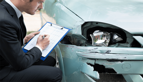 Car accident insurance processing - tycoonstory | tycoonstory media Insurance adjuster inspecting vehicle damage after a car accident and taking notes on a clipboard.