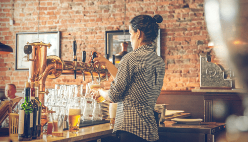 Craft beer - tycoostory | tycoonstory media Brewery staff pouring fresh craft beer behind the bar, highlighting artisanal beer service and pairing experiences