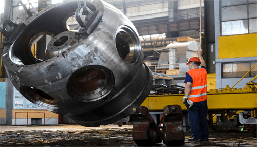 Machinery moving companies | tycoonstory media A worker in safety gear overseeing the lifting of large industrial machinery in a factory setting, illustrating the process of heavy equipment relocation.