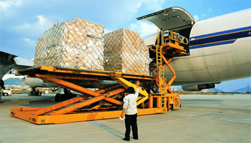 Air freight services - tycoonstory | tycoonstory media Cargo being loaded onto an airplane using a forklift, with large packages wrapped in plastic, highlighting air freight operations at an airport.