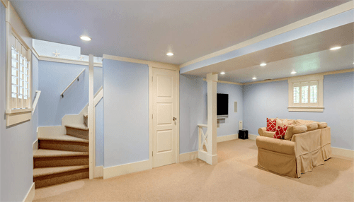 Basement remodeling - tycoonstory | tycoonstory media Bright finished basement with soft lighting, a staircase, and a cozy seating area, showcasing the results of a basement renovation