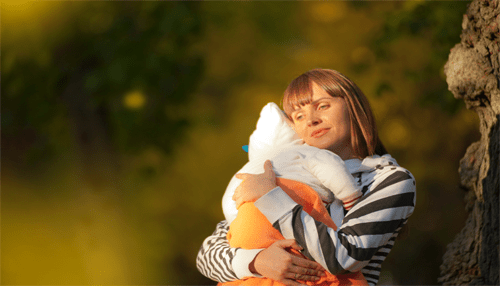 How to financially plan for a new baby A mother tenderly embracing her baby in an outdoor park setting, capturing a quiet moment that highlights the emotional importance of knowing how to financially plan for a growing family.