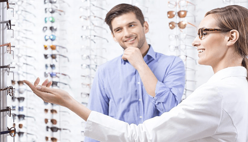 The highs and lows of wearing prescription glasses A customer at an eyewear store discussing prescription glasses options with an optician, symbolizing the journey of finding the right glasses.