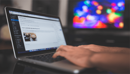 Create your blog - tycoonstory | tycoonstory media A close-up view of hands typing on a laptop displaying a wordpress editor with a blog post draft on the screen.