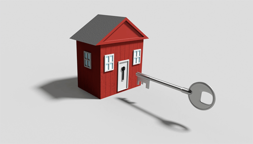 Home loans A small red house with a silver key being inserted into the front door.