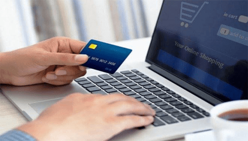 Digital payments - tycoonstory | tycoonstory media Person holding a credit card while typing on a laptop, representing digital payments and online shopping transactions.