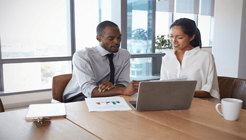 Two professionals discussing data and documents during a business meeting at a well-lit table, highlighting collaboration and teamwork Key due diligence guidelines for examining competition levels