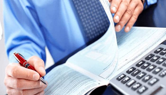 Tax planning tips for small business owners- tycoonstory | tycoonstory media Tax planning: a professional using a calculator and reviewing financial documents for effective tax planning and business management.