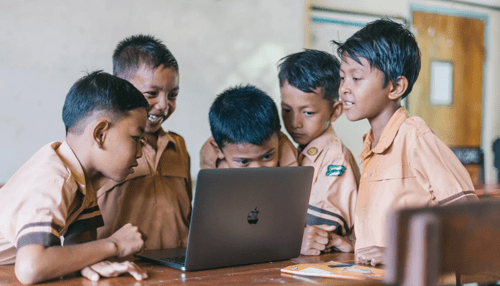 Macbook air Group of school children gathered around a macbook air laptop while learning and exploring technology together.