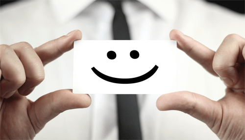 Press kit A businessman holding a card with a smiley face, symbolizing positivity and branding, important elements in a press kit.