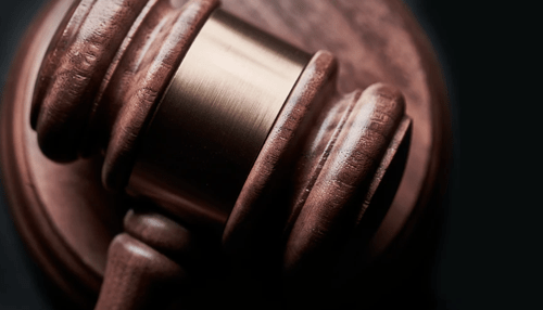 Criminal lawyer A close-up, dramatic shot of a wooden criminal lawyer gavel resting on a sound block, highlighting the polished wood grain and gold band.