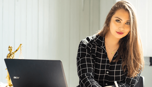 Stratum business intelligence Professional woman working on a laptop in an office with legal decor, highlighting productivity and business intelligence tools.