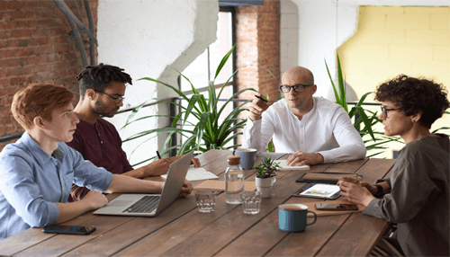 Empowering-tycoonstory | tycoonstory media Employees engaged in a collaborative brainstorming session, using laptops and notes in a creative office environment.