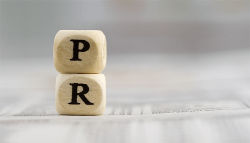 Two wooden blocks displaying the letters'P' and 'R' representing public relations, set against a blurred background Reasons why public relations is important for a business