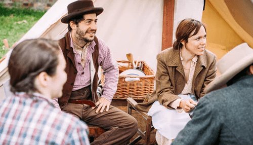 Schedule time for your family and friends - tycoonstory' | tycoonstory media Group in period costume sitting and chatting outdoors. Emphasizes the intersection of work and private life.