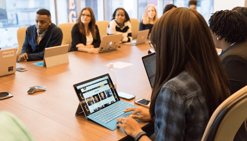 Wear for business, tech, and start-up meetings - tycoonstory | tycoonstory media Business team in a meeting room using laptops, highlighting formal wear for business in a professional workspace.