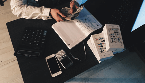 Financial health Counting cash on a desk with phones and a calculator, illustrating management of funds for good financial health.