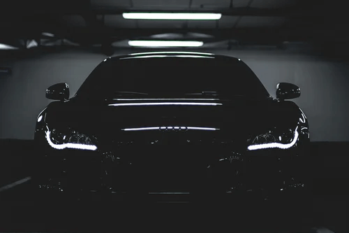 Keep maintaining it - tycoonstory | tycoonstory media A sleek black luxury car in a dimly lit garage with headlights glowing, creating a dramatic automotive scene.