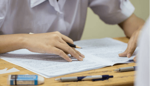 Neet Student reviewing notes and writing answers on paper while preparing for a mock test.