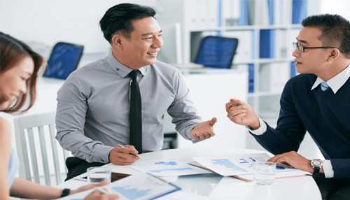 Communication-skills-tycoonstory | tycoonstory media A group of financial analysts in a meeting, discussing reports and financial data in a modern office setting, with documents and charts on the table.